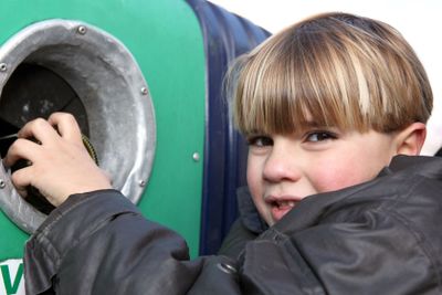 Little boy throwing a glass bottle in a container