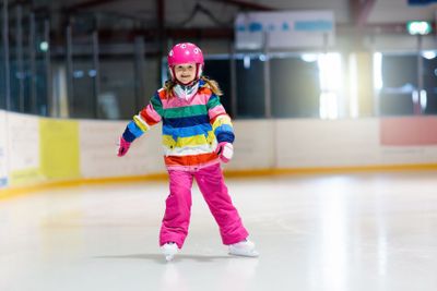 Child skating on indoor ice rink. Kids skate.