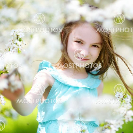 Adorable little girl in blooming cherry garden