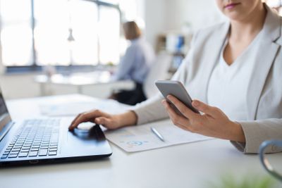 businesswoman with smartphone and laptop at office