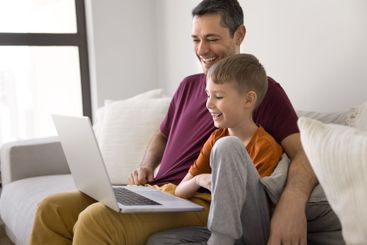 Joyful father and son spend time on internet using laptop