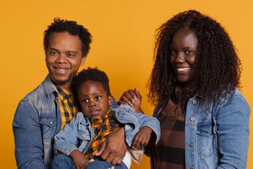 African american family smiling against yellow...