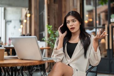 A moody, dissatisfied Asian businesswoman is talking on...