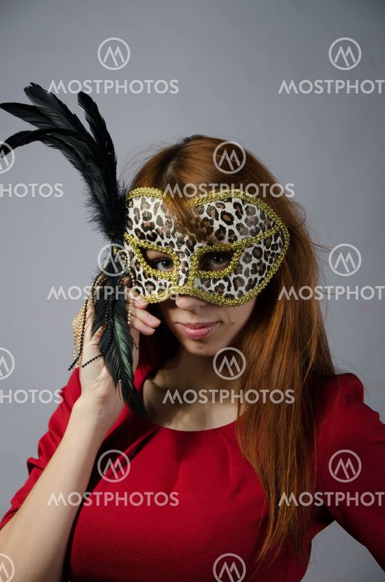 Beautiful young girl in a red dress and mask