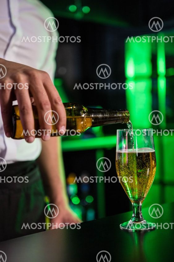 Mid section of bartender pouring beer in a glass
