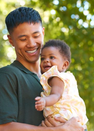 Family Shot With Loving Father Cuddling Baby Daughter...