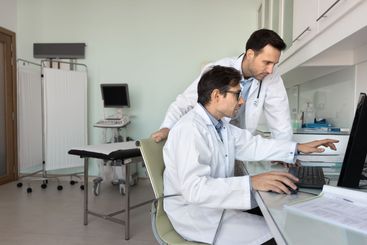Two focused male doctors reviewing ultrasound...