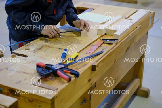 A carpenter measures a bar of wood with a ruler for...