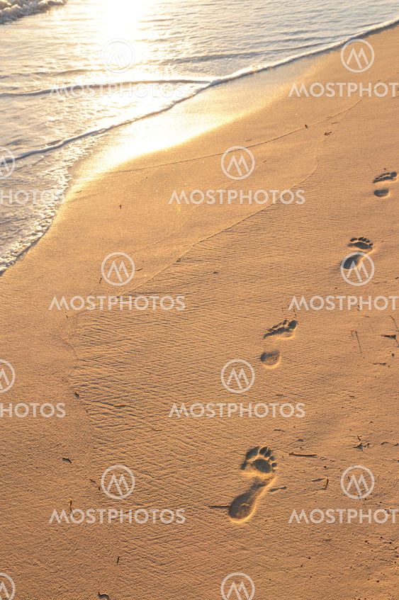 Footprints on sandy beach at sunrise