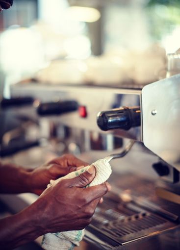Man, hands and cleaning coffee machine in shop, closeup...