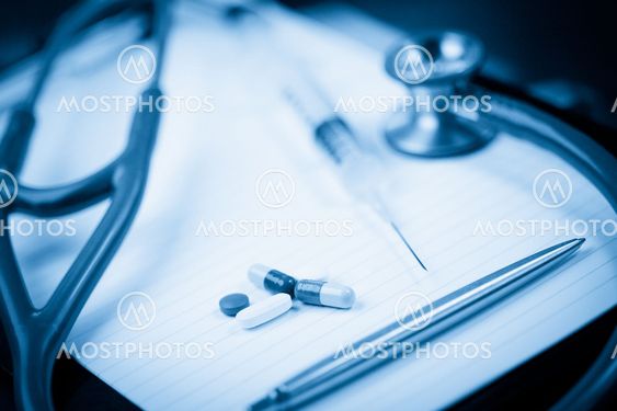 Note pad with stethoscope and pen along with serynge and capsules