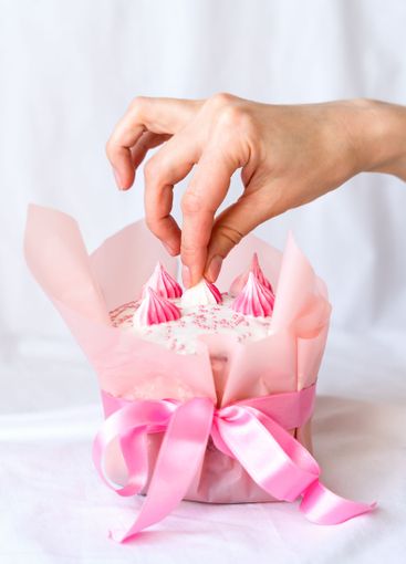 The hands of a young woman decorate an Easter cake....