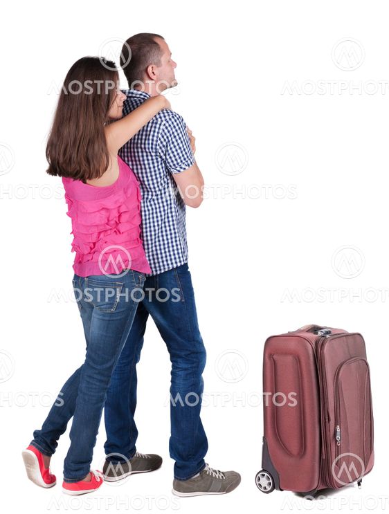 Back view of young couple traveling with suitcas .