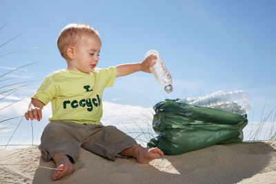 Baby Boy Collecting Bottle In Plastic Bag On Beach