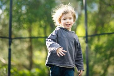 Little boy jumping on a trampoline in a backyard on warm...