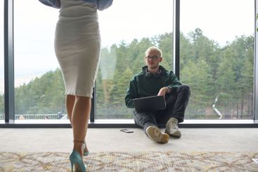 A blonde man sitting casually on the floor of a modern...