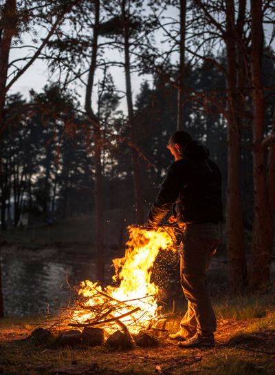 Man lights a fire in the fireplace in nature