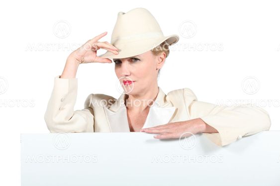 Woman wearing creme coloured hat and jacket stood with message board