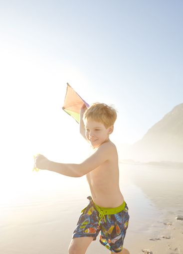 Beach, boy and running with kite for playing, childhood...
