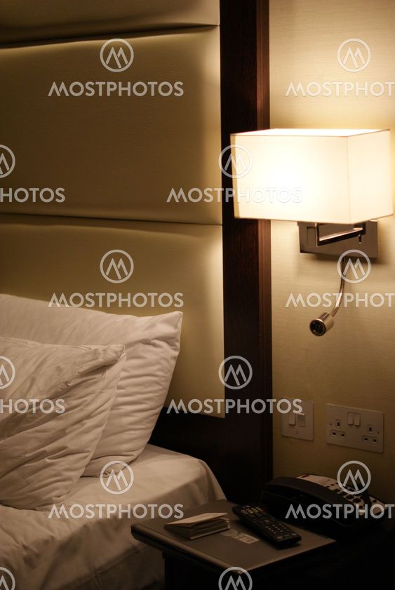 Laptop, Telephone and TV Remote against a bed