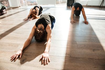 Group of people doing yoga on wooden floor in studio