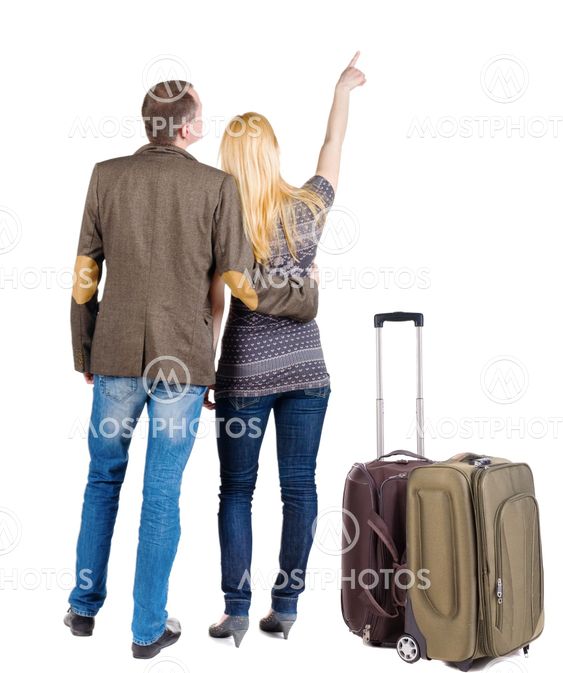 young couple traveling with suitcas and pointing at wal...