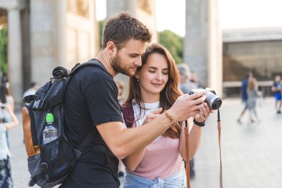 young couple of travelers looking at photo camera at...