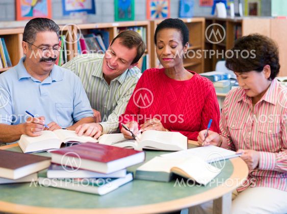 Teacher helping mature students in library