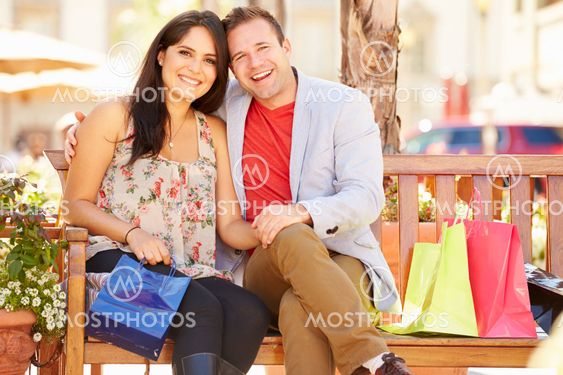 Young Couple Resting With Shopping Bags Sitting In Mall