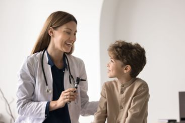Laughing young female doctor talking to patient kid...