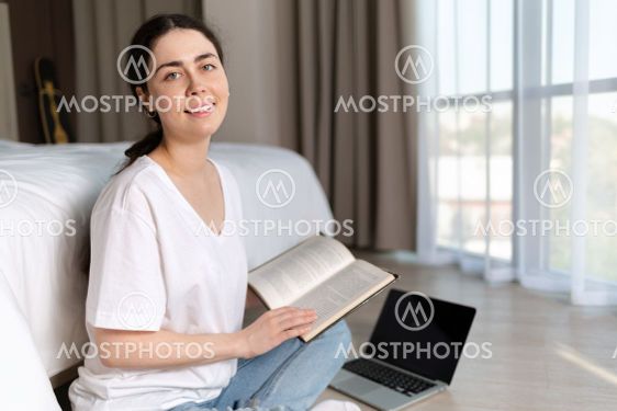 Portrait of young smiling woman is sitting on the floor...