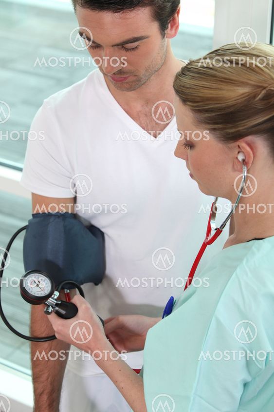 Young nurse taking blood pressure of a man