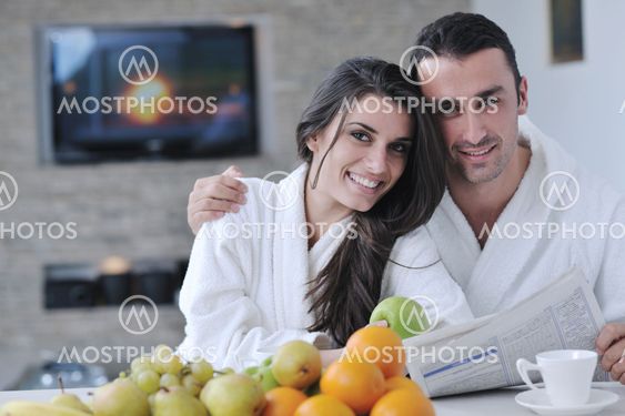 Happy couple reading the newspaper in the kitchen at breakfast