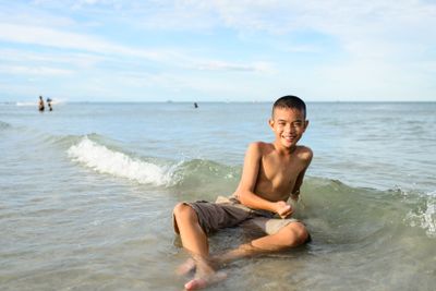 smiling boy sitting on the beach