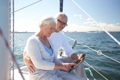 senior couple with tablet pc on sail boat or yacht