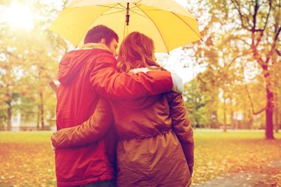 happy couple with umbrella walking in autumn park