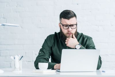 portrait of focused businessman working on laptop at...