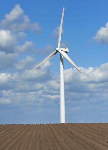 Wind turbine, blue sky and wheat field with farmland for...