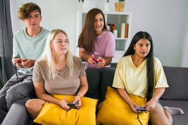 Friends playing video games together at home, leisure...