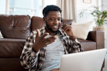 Black man, laptop and headset in home for remote work,...