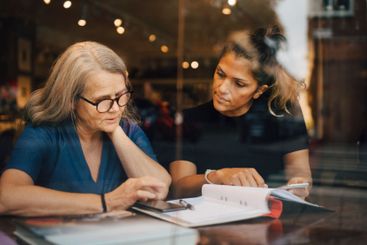 Businesswoman discussing with female coworker over smart...