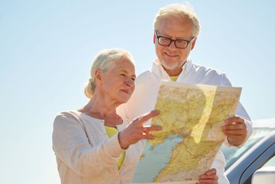 senior couple at car looking for location on map