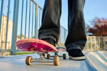 Skateboarder riding on pink skateboard at skatepark