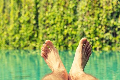 close up of male feet over resort swimming pool