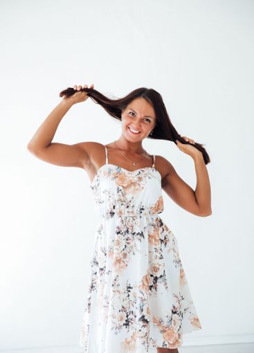 Brunette woman in summer dress holding her hair with her...