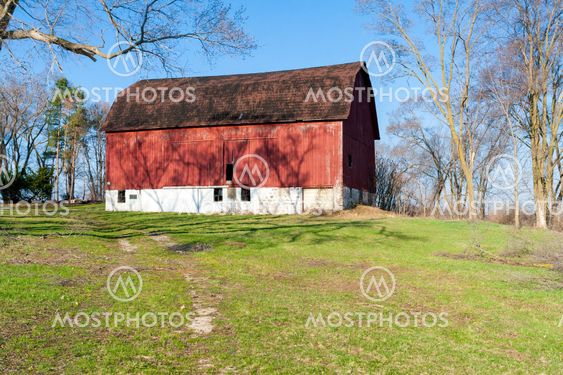 A weathered red barn on a hill