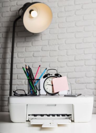 Home office workspace with printer, desk clock, and...