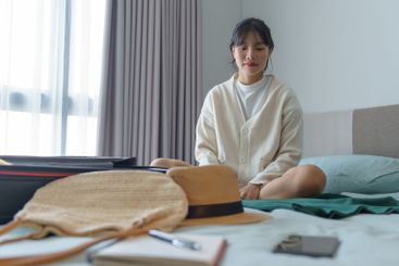 Woman packing suitcase on bed for a new journey packing...