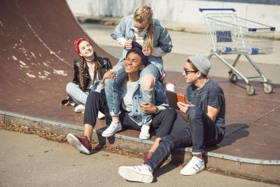 Teenagers group sitting together on the ramp and having...