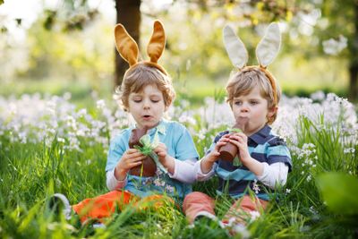 Two little boys wearing Easter bunny ears and eating...